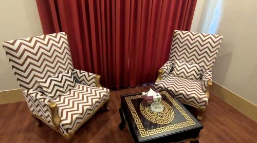 two chairs and a table in front of a curtain at Hotel The Holiday in Lahore