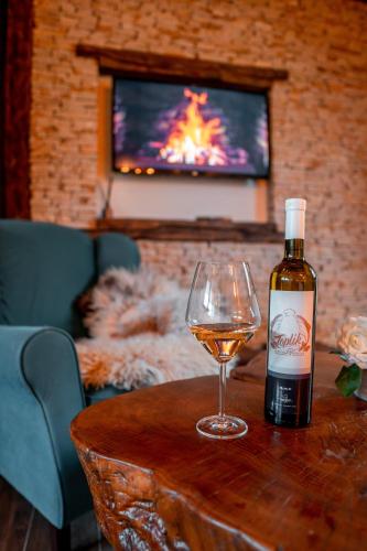 a bottle of wine and a glass on a table at Toplik Village Resort in Lukavica