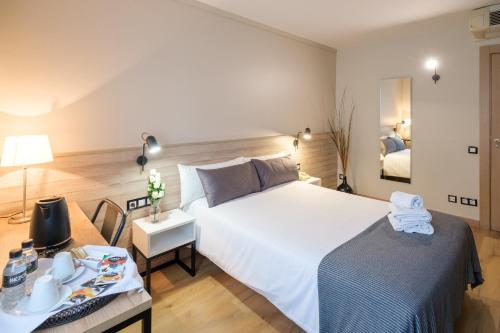 Un dormitorio con una gran cama blanca y una mesa en Hotel Torres Manlleu, en Manlleu