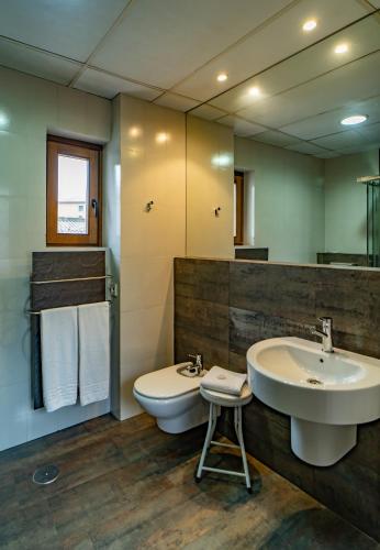 a bathroom with a sink and a toilet and a mirror at Hotel Alfonso IX in Cáceres