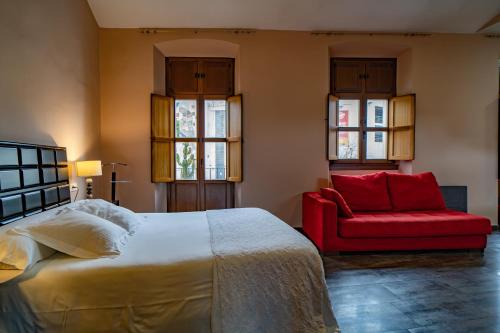 a bedroom with a bed and a red couch at Hotel Alfonso IX in Cáceres
