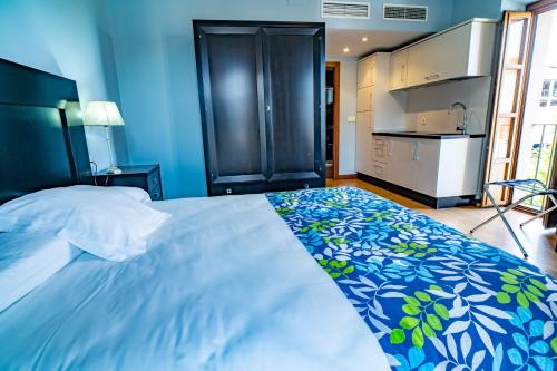 a blue bedroom with a large bed and a kitchen at Hotel Alfonso IX in Cáceres