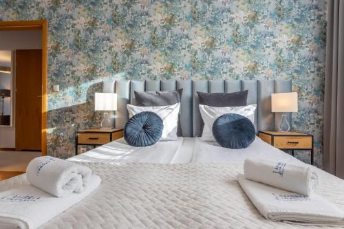 ein Schlafzimmer mit einem großen weißen Bett mit blauen Kissen in der Unterkunft Ambria Apartments Platan Complex in Świnoujście