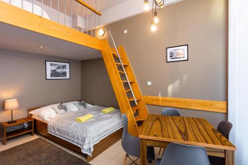 1 dormitorio con litera, mesa y sillas en Apartamenty Brzozowa - Centrum en Zakopane