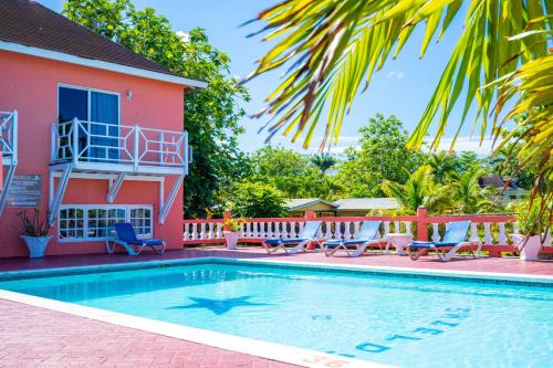 a swimming pool in front of a house at Shields Negril Villas in Negril