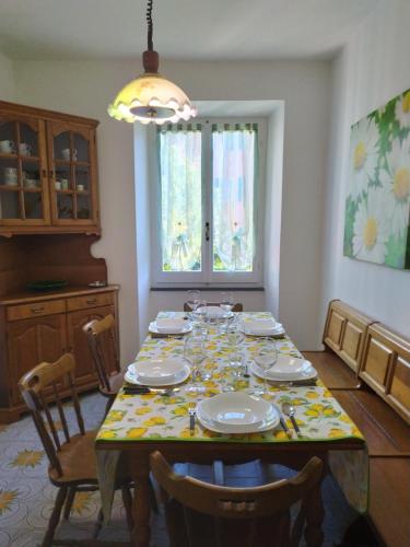 uma sala de jantar com uma mesa com pratos e cadeiras em Casa Iris em Borzonasca