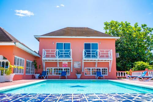 a villa with a swimming pool in front of a house at Shields Negril Villas in Negril