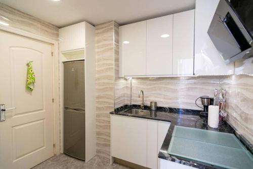 - une cuisine avec des placards blancs, un évier et une porte dans l'établissement La Caleta de Mogro, à Mogro