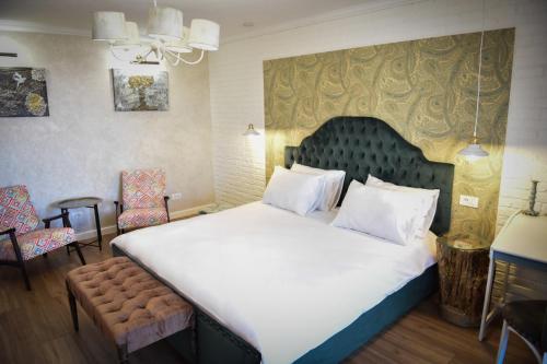 ein Schlafzimmer mit einem großen weißen Bett und Stühlen in der Unterkunft Restauro Apartament in Buzău