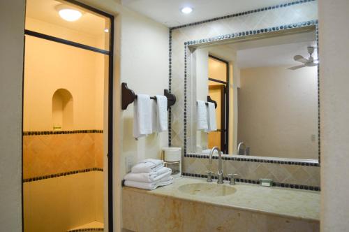 baño con lavabo y espejo grande en Casa Celeste Hotel en Zihuatanejo