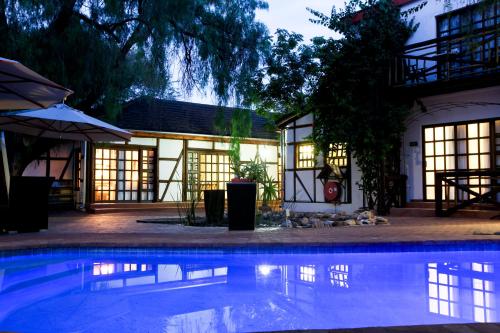 a swimming pool in front of a house at night at Roof of Africa Hotel in Windhoek