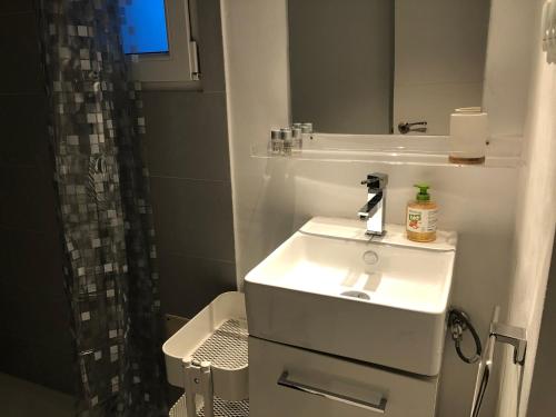 a white bathroom with a sink and a mirror at ESTUDIO MAESO con sofá cama in Manzanares el Real