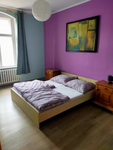 a bedroom with a bed and a purple wall at Wleń Rynek in Wleń