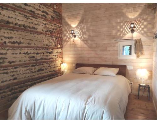 a bedroom with a white bed with a brick wall at Duplex de L'Artisterie in Mondonville