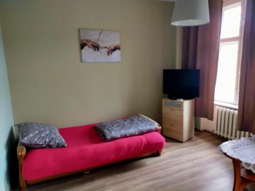 un sofá rojo en una habitación con TV en Wleń Rynek, en Wleń