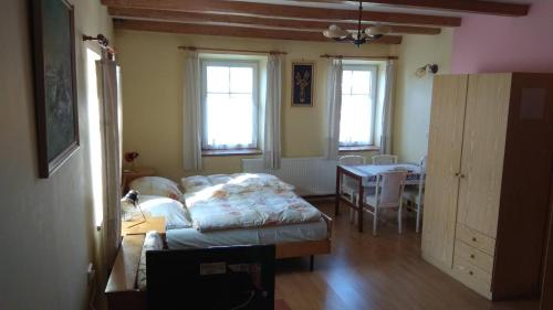 a room with a bed and a table and windows at Turistická základna u Nývltů in Martínkovice