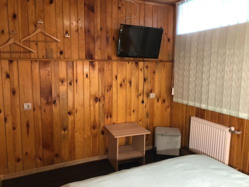a room with a bed and a tv on a wooden wall at Apartment complex in Sumy
