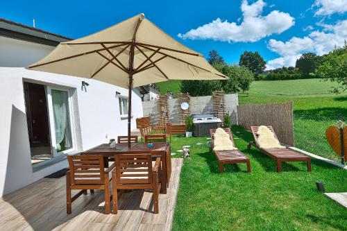 a wooden table and chairs with an umbrella at La Maisonnette Enchantée in Prez-vers-Siviriez
