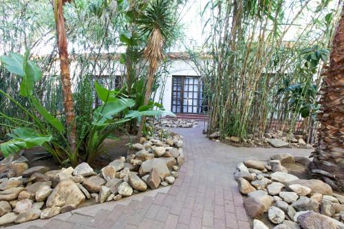 a walkway through a garden with rocks and trees at Roof of Africa Hotel in Windhoek