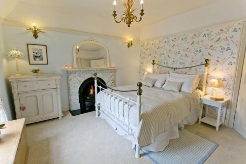 a bedroom with a white bed and a fireplace at Bay House in Beaumaris