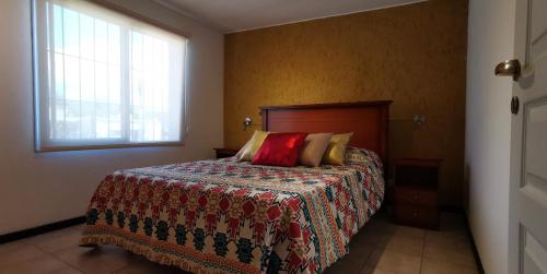 Un dormitorio con una cama con una colcha de colores y una ventana en Belgrano Apartment con cochera en Mendoza