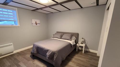 a bedroom with a bed and a window at Condo-chalet de la Vallée d'Édouard in LʼAnse-Saint-Jean