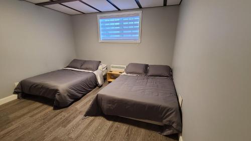 2 Betten in einem Zimmer mit Fenster in der Unterkunft Condo-chalet de la Vallée d'Édouard in LʼAnse-Saint-Jean