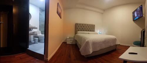 a small bedroom with a bed and a bathroom at Hotel Colonial Andino - Parque principal de Pitalito in Pitalito