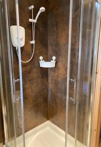 a shower with a glass door and a sink at Dove Cottage (Annex) in Workington