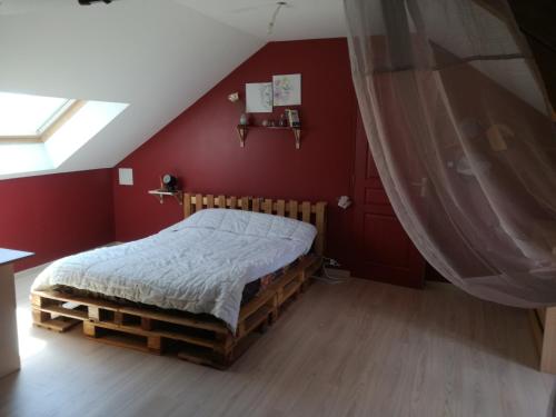 um quarto com uma cama numa parede vermelha em Chambre à Villemandeur Chez L'habitant em Villemandeur