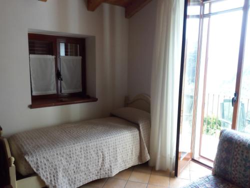 a bedroom with a bed next to a window at APPARTAMENTO FERRARO TURINA in Motta Camastra