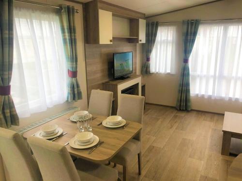 a dining room with a table and chairs and a television at Oak Prestige Holiday Home in Chapel Saint Leonards