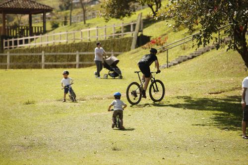 a man on a bike and two children in a field at Hotel Fazenda Dona Carolina in Itatiba