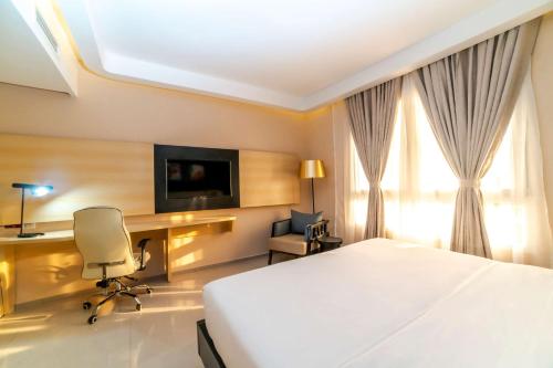 a hotel room with a bed and a desk and a tv at Best Western Plus Soaho Douala Airport in Douala