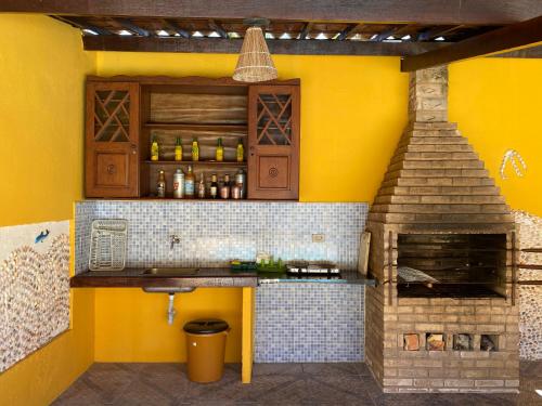 a kitchen with a brick oven and yellow walls at Vila Japaraiso-Casa Amarela Próxima ao mar in Japaratinga