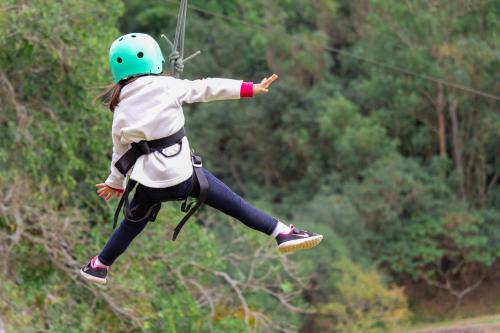 a girl in a helmet jumping on a zip line at Hotel Fazenda Dona Carolina in Itatiba