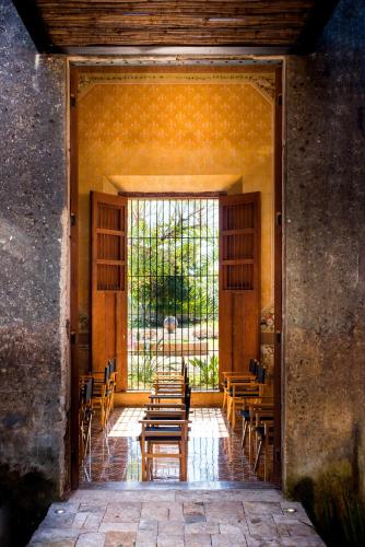 a room with chairs and tables and a large window at Hacienda San Antonio Hool in Mérida