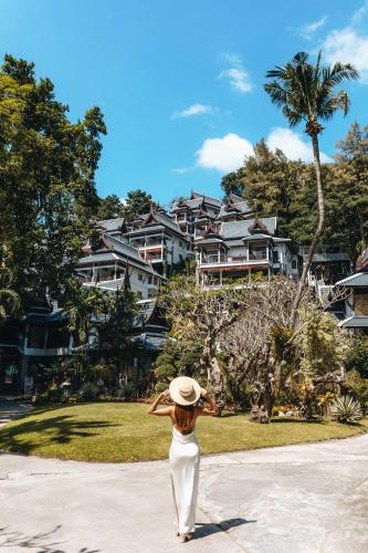 a woman wearing a hat standing in front of a house at Thavorn Beach Village Resort & Spa Phuket in Kamala Beach