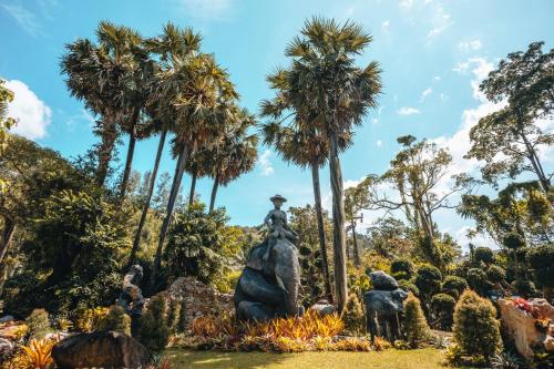 a statue in a park with palm trees at Thavorn Beach Village Resort & Spa Phuket in Kamala Beach
