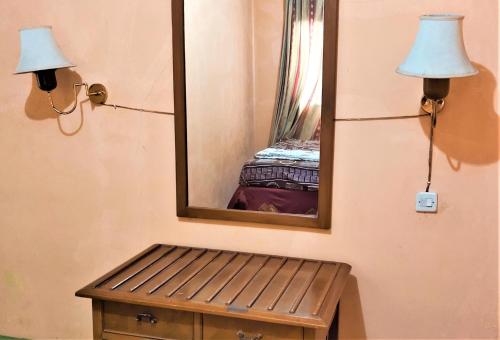 a mirror on a wall with a bench and a lamp at Villa Orange Lembang Pengkolan in Lembang