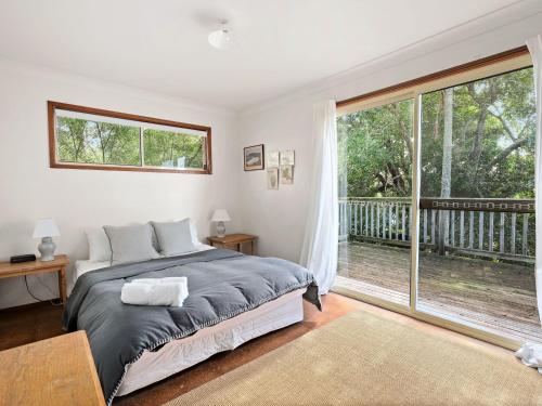 a bedroom with a bed and a large window at Spacious Adventure Getaway by the Bush & Ocean in Macmasters Beach