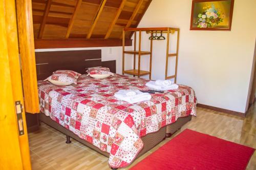 a bedroom with a bed with a red and white quilt at Pousada Vale Verde in Monte Verde