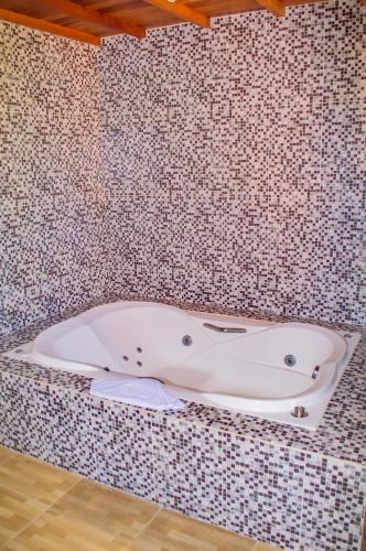 a bath tub in a bathroom with a tiled wall at Pousada Vale Verde in Monte Verde