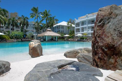 een groot zwembad met rotsen voor een gebouw bij Beach Club Private Apartments Palm Cove in Palm Cove