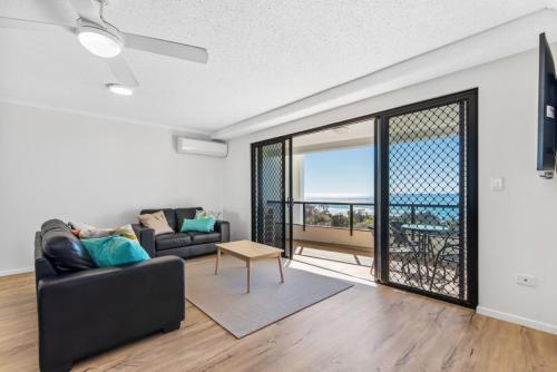 a living room with a couch and a large window at San Marino by the Sea Apartments in Marcoola