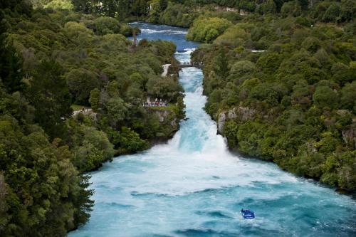 a boat in a river with a waterfall at Alpine Lake Motel in Taupo