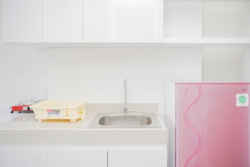 a kitchen with a sink and a pink refrigerator at Comfy 2BR Apartment at Parkland Avenue By Travelio in Babakan