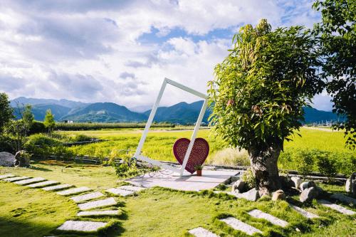 a garden with a chair and a tree in a field at 禾田遇民宿 Hetianyu in Sanxing