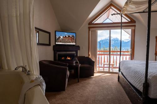 1 dormitorio con chimenea, 1 cama y TV en A Bear and Bison Country Inn, en Canmore