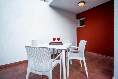 a white dining room table with two glasses of wine at StayVista at Saanu Ki Villa with free Breakfast in Candolim